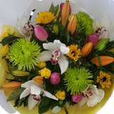 A vibrant bouquet of multi-colored flowers including white, yellow, green, pink, and orange flowers, arranged in a round shape.