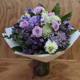 Bouquet of purple roses and white flowers on a wooden surface