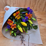 Bouquet of colorful flowers- blue, yellow and orange wrapped in brown paper.