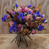 Bouquet of dried flowers with blue, pink, and brown tones on a wooden surface.