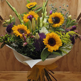 Bouquet of sunflowers and other flowers wrapped in white paper.