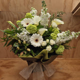 A white and green bouquet of flowers. The flowers are stock, spray roses, lilies, alstroemaria and gerberas.