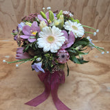 a posy in a vase of gerbera, protea, lilies orchids etc