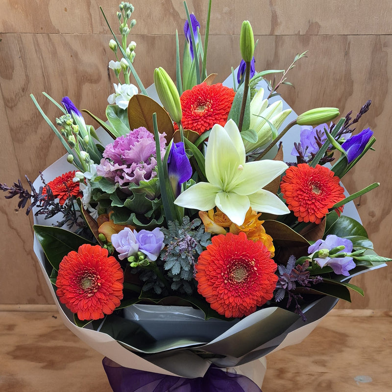 Bouquet of colorful flowers with red, orange, and purple and white flowers arranged in a water-box.
