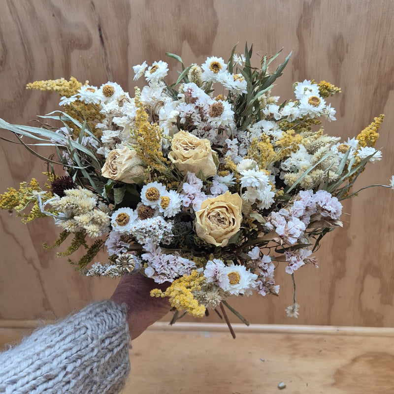 Bouquet of dried flowers held by a person against a wooden background