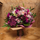 Bouquet of different shades of pink flowers, wrapped in pink craft paper.