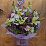 A bouquet of cream lilies, mauve flowers, white spray chrysanthemum and snapdragons.