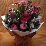 Striking pink Protea and calla lilies, complimented by straw flowers, ammobium, statice and dark green foliage. This bouquet is presented in a water box and wrapped in craft paper