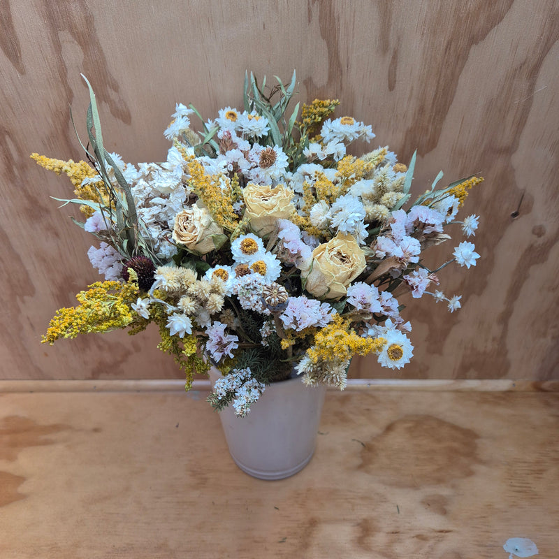 A dried floral bouquet featuring a mix of soft creamy shades, with white and a touch of yellow flowers, arranged in a naturalistic style.