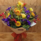 Bouquet of colorful flowers with a red ribbon on a wooden surface