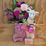 a box to welcome a baby containing flowers, a giraffe soft toy, hand knitted bootees and hat, and a hand cream and soap
