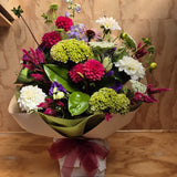 Bouquet of colorful flowers with a red ribbon on a wooden surface