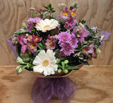 a mixed bouquet of mauve and pink flowers, in a water box.