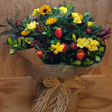 Bouquet of flowers wrapped in brown paper in a water box, with a bow on a wooden background