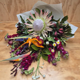 Bouquet of flowers with a prominent protea on a wooden surface