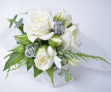 mini white roses and foliage arranged into a dainty wrist corsage.